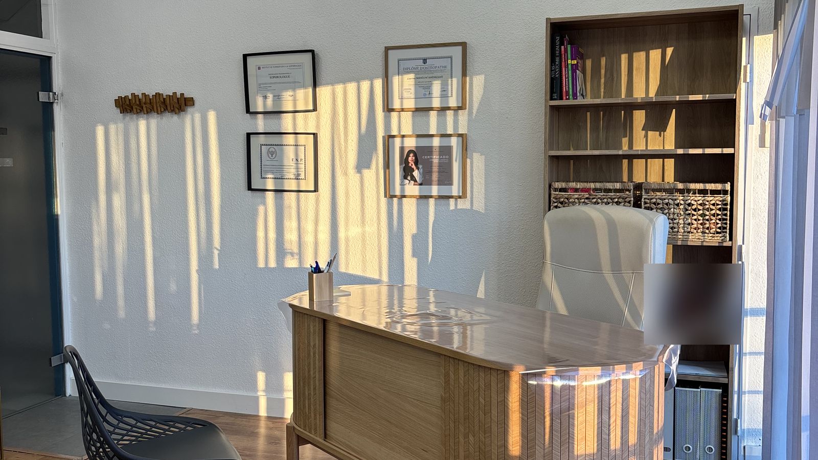 Le cabinet de Laurina Manzon Andreani à Allauch : bureau en bois clair et diplômes d'ostéopathe encadrés au mur